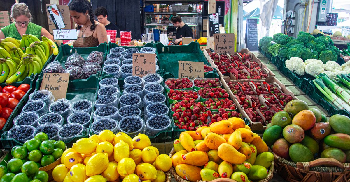 Fresh fruits and vegetables beautifully arranged at an outdoor market stall, showcasing a variety of produce and healthy options.
